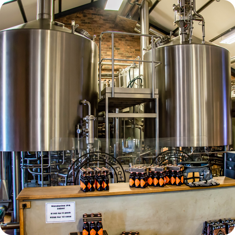 Brewery with large metal tanks and a display of beer bottles on a counter.